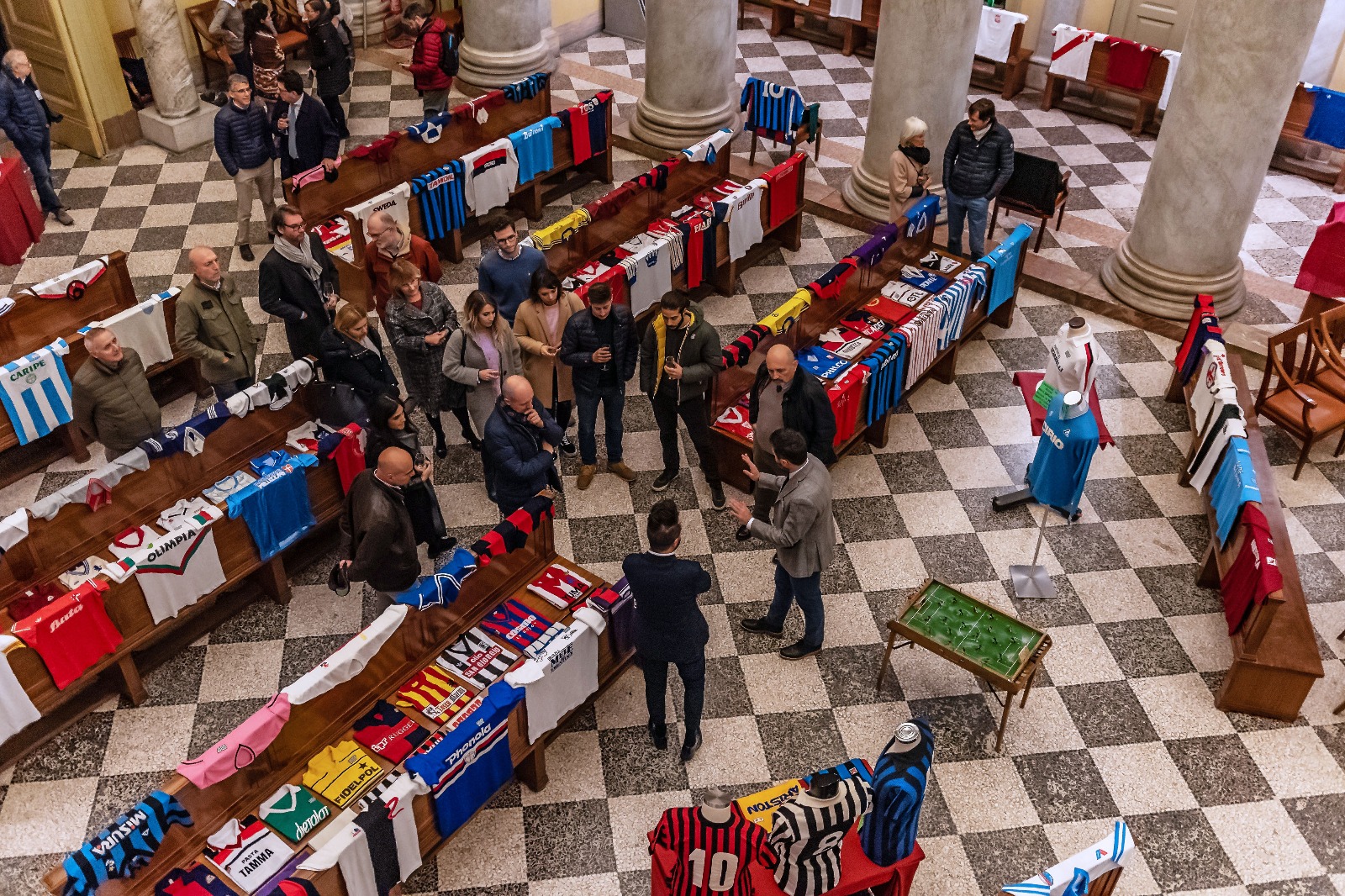 Panoramica dall'alto con visitatori e maglie sui banchi