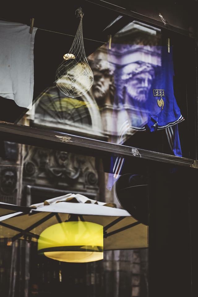 Maglia azzurra e pallone in vetrina con riflessi